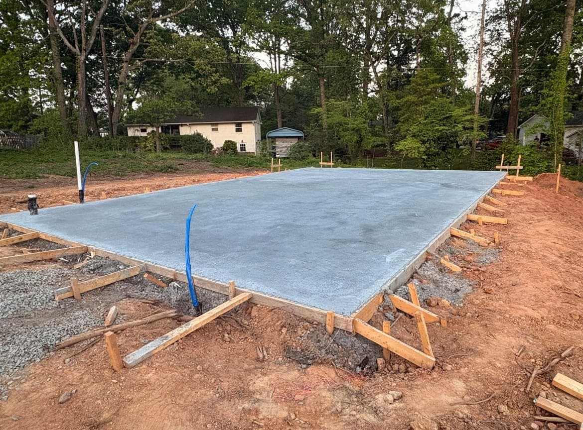 Concrete foundation slab installation in Charlotte, NC — poured footings, control joints, smooth troweled surface by Local Concrete Contractor.